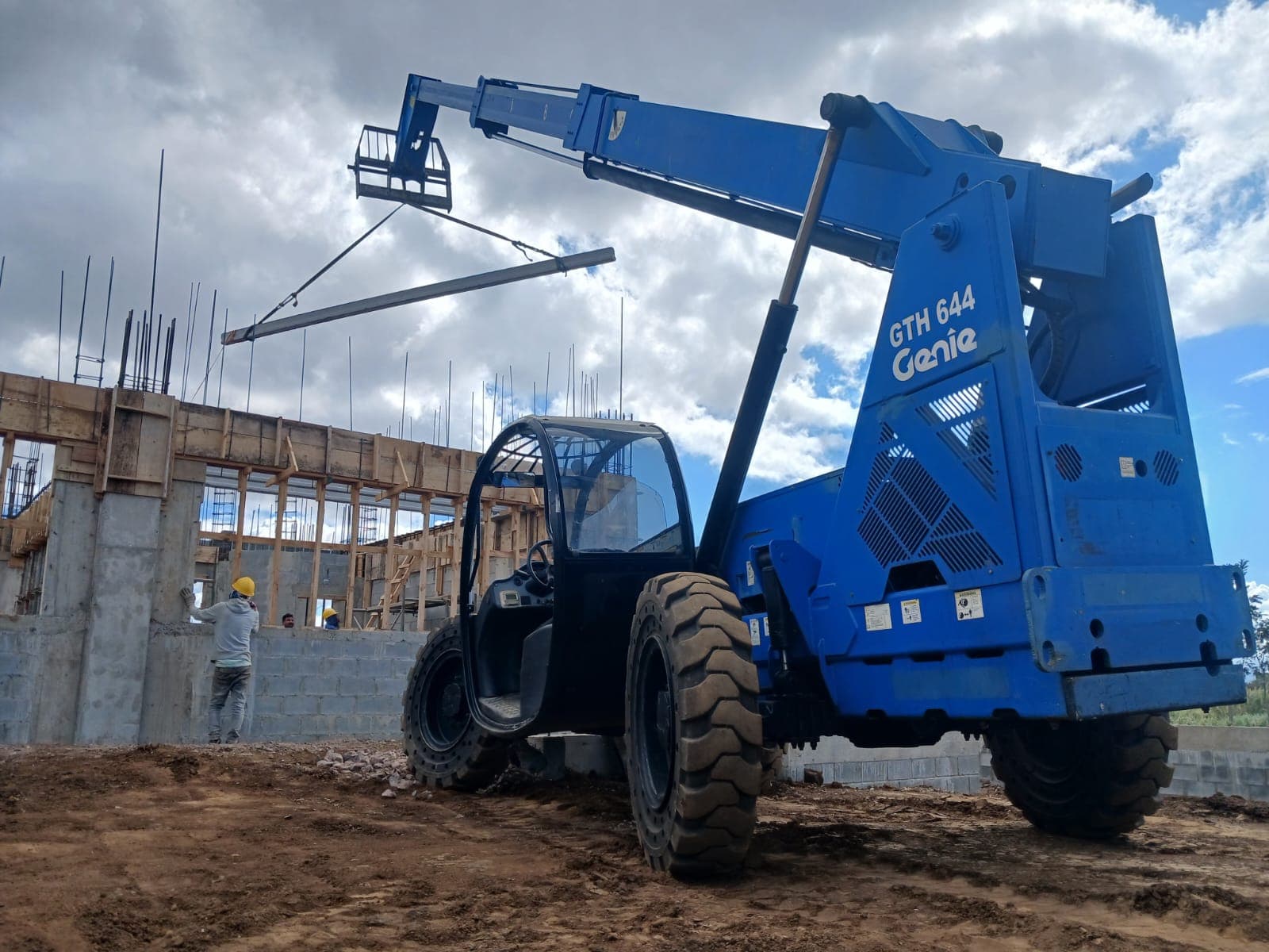 Telehandler Genie GTH-644 levantando una viga junto a una estructura en construcción